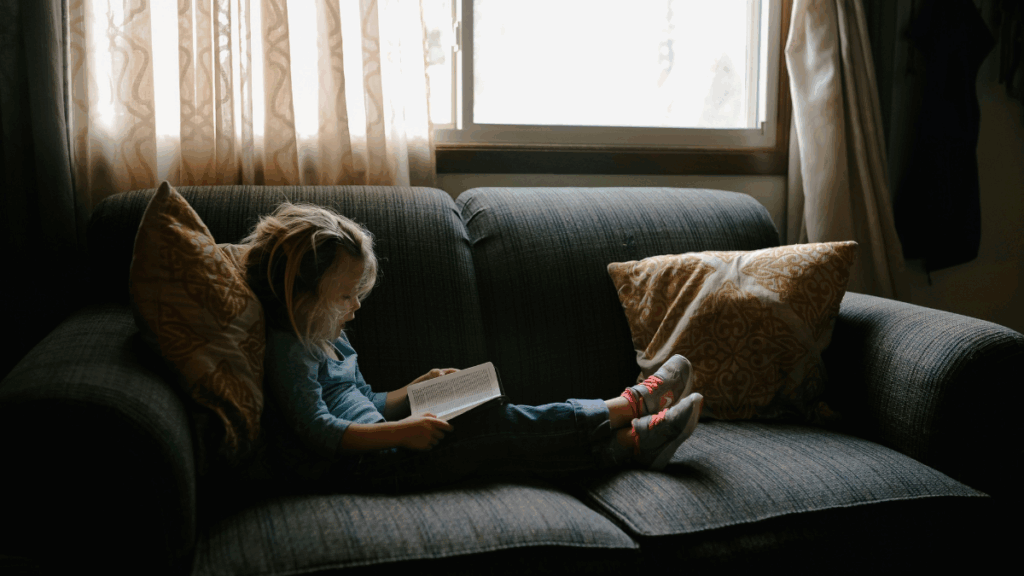 little girl reading on a couch