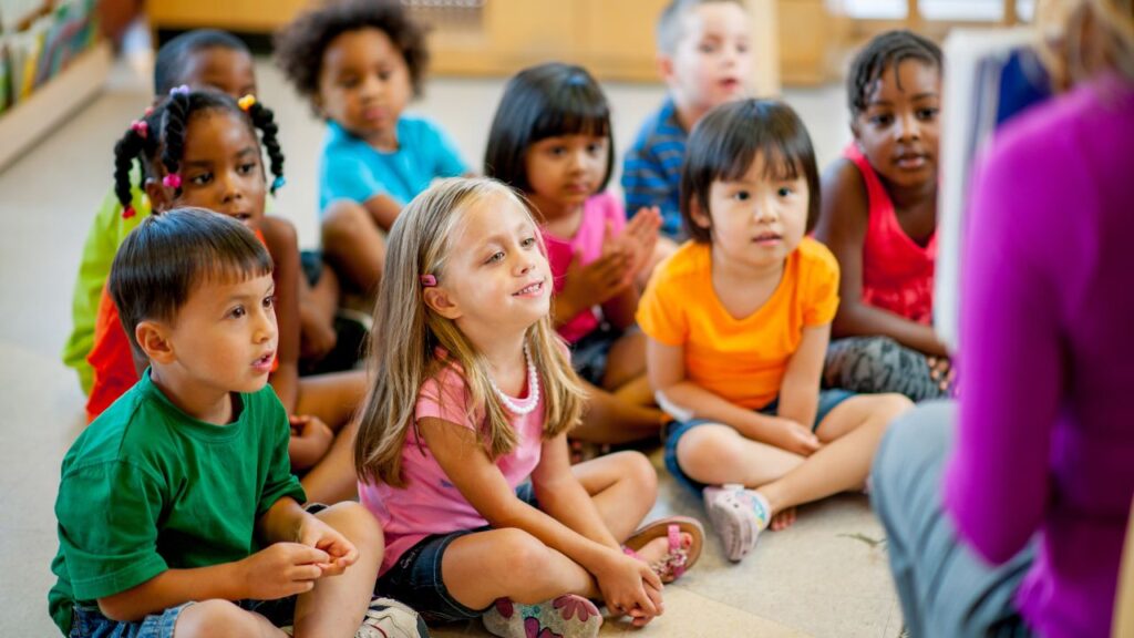 Students seated on the floor listening to the teacher