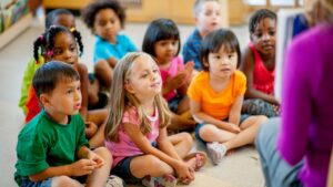 Students seated on the floor listening to the teacher