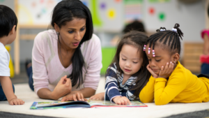 Teacher with students reading a book.