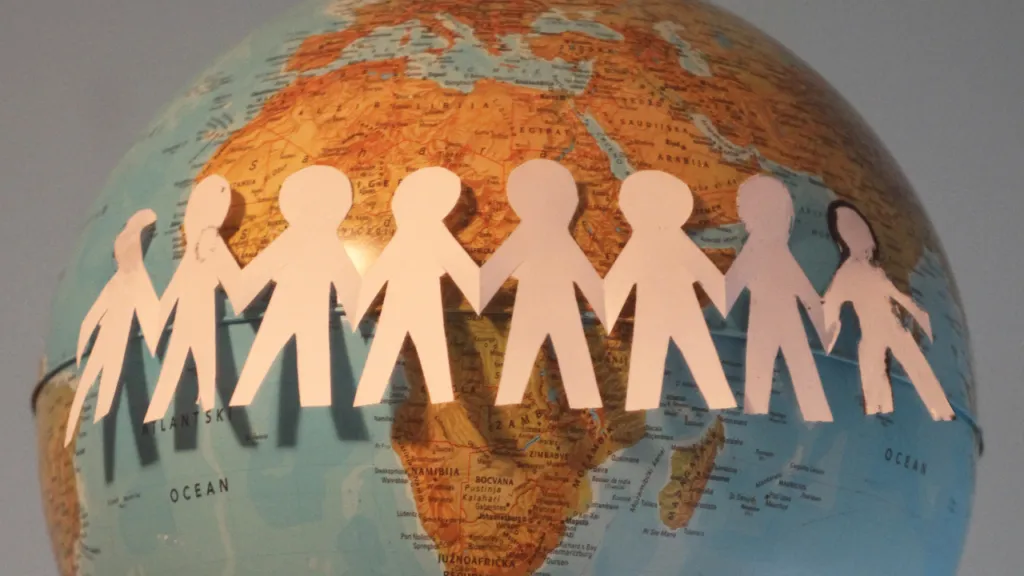 Paper figures holding hands around a globe