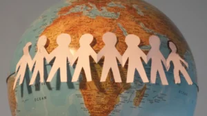 Paper figures holding hands around a globe