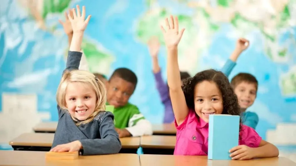 Students with their hands raised in a classroom.