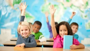 Students with their hands raised in a classroom.