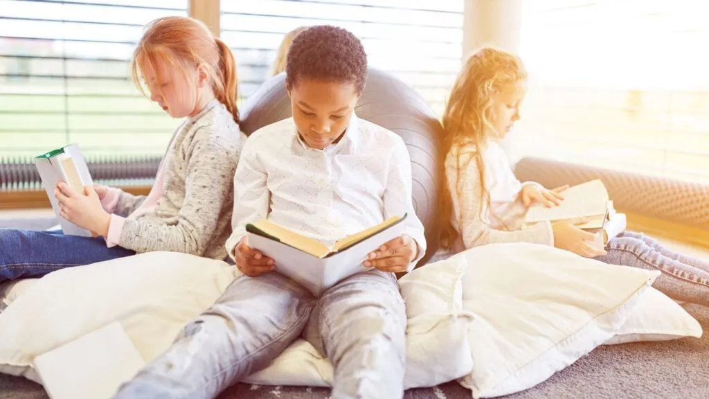 Three children sit in a circle reading books together