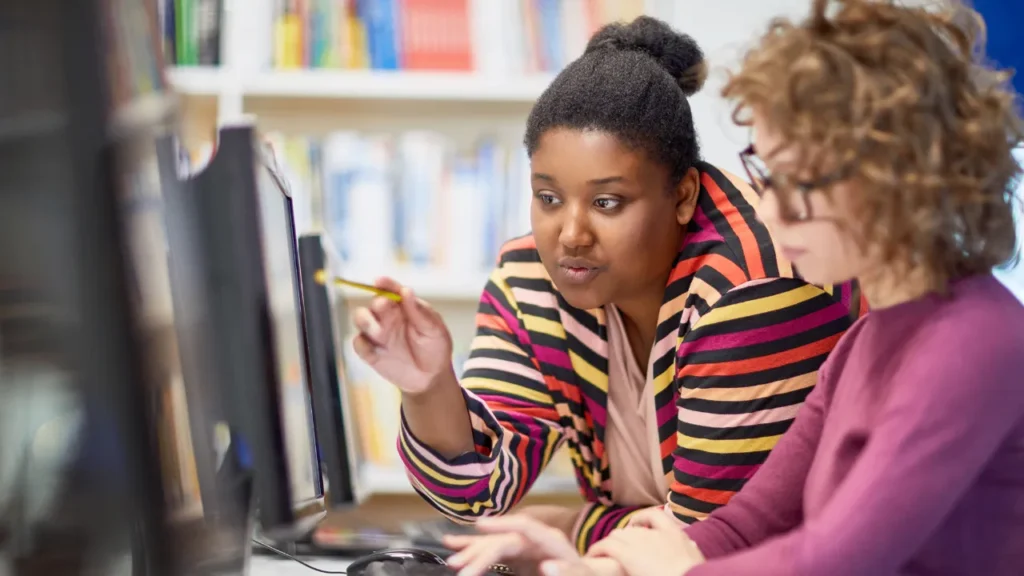 Two colleagues reviewing data on a computer.